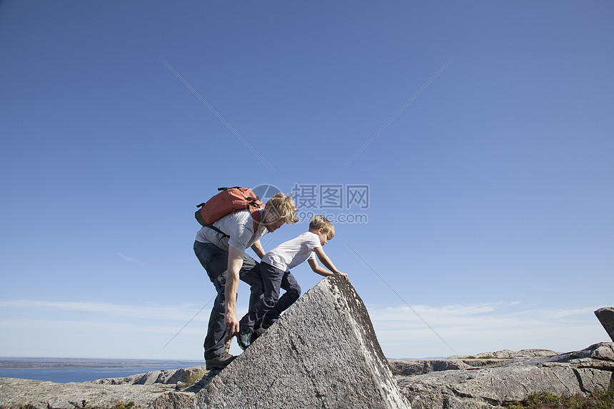 男孩和父亲在海岸入口处攀岩图片