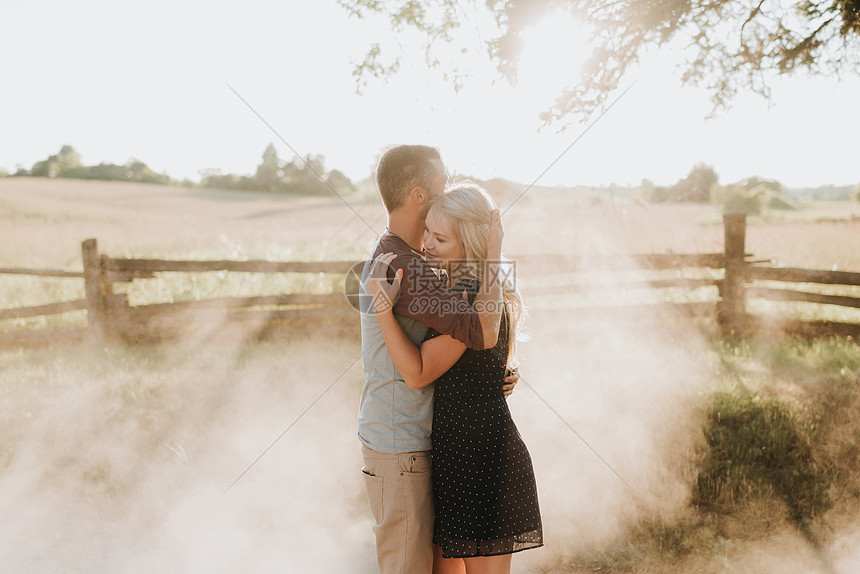 日落时在有灰尘的泥土轨道上浪漫的男人和女友拥抱图片