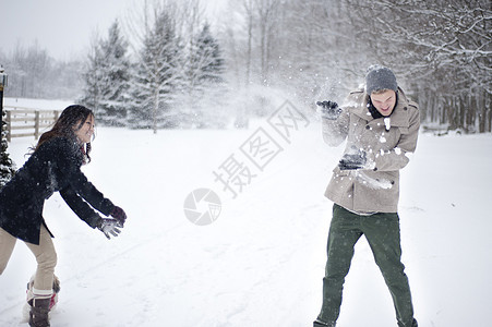 在加拿大安略省雪覆盖森林中打球的年轻夫妇图片