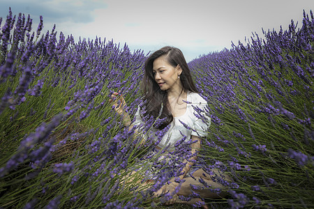 长棕色头发的中成年妇女在熏衣草地交叉穿行图片