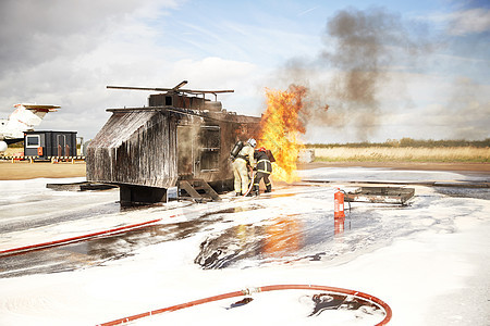 消防员培训小组在训练设施模拟直升机消防时喷泡沫图片
