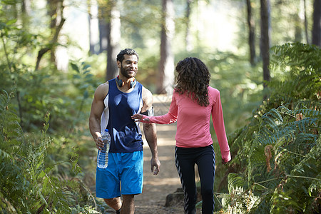在森林中分享瓶装水的男女慢跑者图片