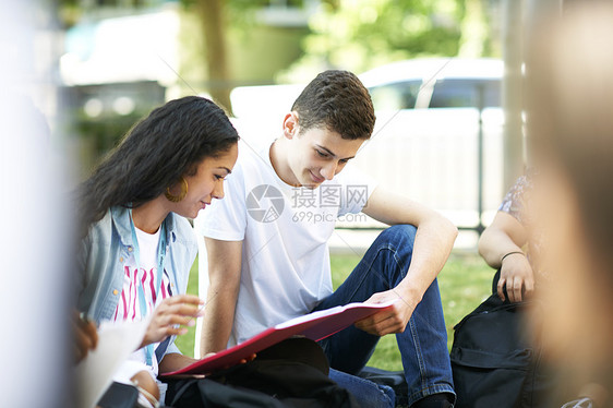 在大学校园草坪上看文案的男女同学图片