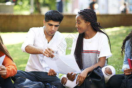 男女高等教育学生在大校园草坪上讨论文书工作图片