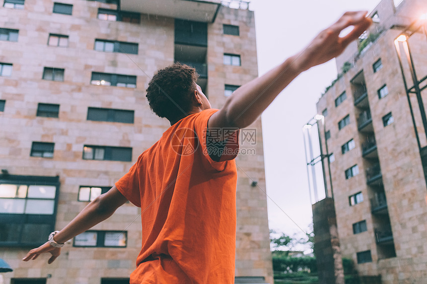 男人在雨中张开双臂抬起头意大利米兰市广场图片