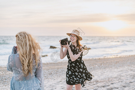 沙滩上拍摄朋友的年轻女子图片
