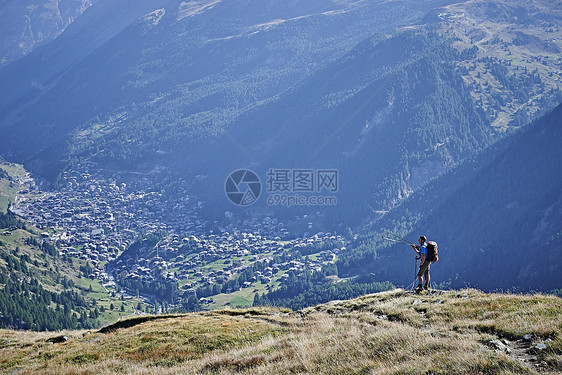 在草悬崖上看山谷的登山者瑞士瓦莱州图片