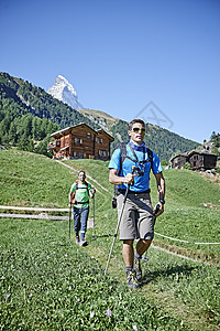 瑞士瓦莱斯马特洪峰塞文山走在田野的小屋前的徒步旅行者图片