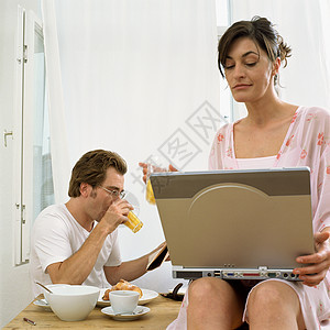 早餐时看笔记本电脑的一对夫妇图片