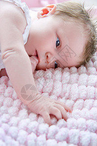 躺在毛毯上吸着手指的婴儿图片