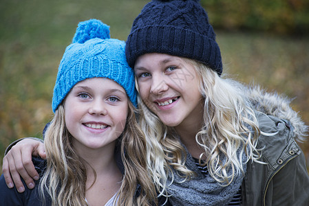 在花园里戴着毛线帽的金发姐妹在微笑高清图片