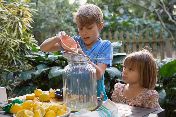 男孩和妹妹在花园桌前倒柠檬汁图片
