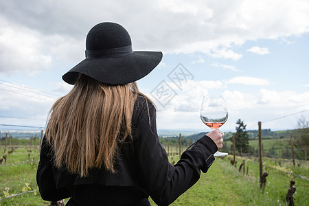 女人站在葡萄园里拿着酒杯背影图片