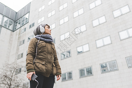 中成年妇女低角度收听耳机观看城市办公室街区图片