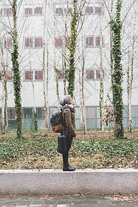 站在办公建筑墙壁上的女人背着包图片