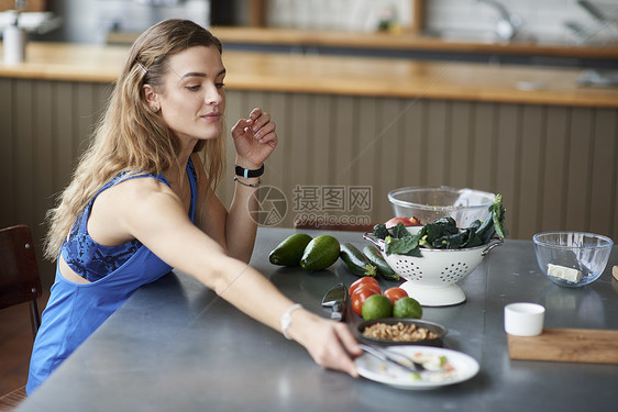 厨房餐桌上的年轻女士去拿沙拉盘子图片