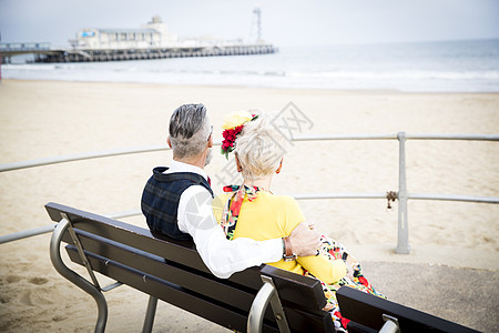 沙滩长椅上坐着的一对打扮复古的老年夫妻图片