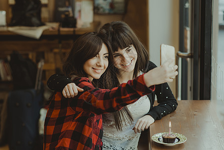 两个女人坐在咖啡馆用手机自拍图片