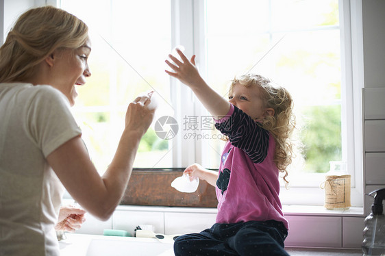 母亲和女儿在厨房柜台上玩泡泡图片