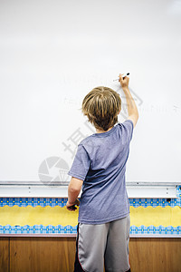 年轻男孩在白板上写作图片