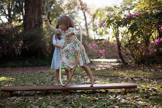 女孩在花园里穿过塑料圈跑图片