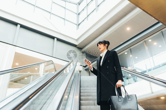 在扶梯上使用移动电话的意大利米兰女商人图片