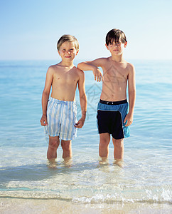 两个男孩站在大海里图片
