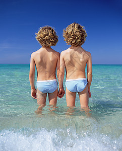二个男孩站在海中图片