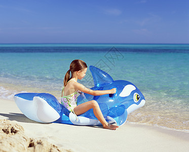 女孩在海滩上玩卡通充气游泳坐垫图片