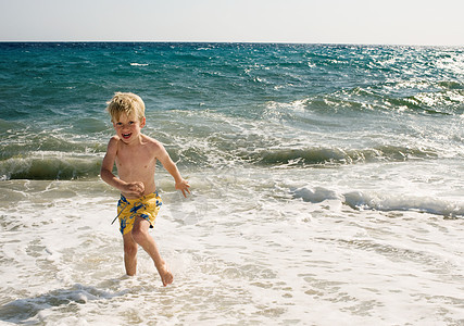 浅水海滩上的小男孩图片