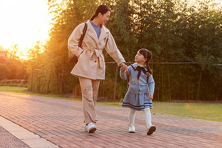 妈妈牵手夕阳下妈妈接女儿放学背景