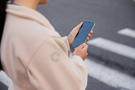 青年女性过马路拿手机特写图片