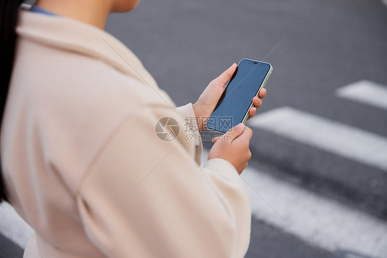 青年女性过马路拿手机特写图片