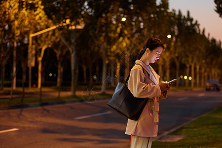 年轻女性下班马路旁等待背景图片