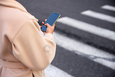 青年女性过马路看手机特写图片