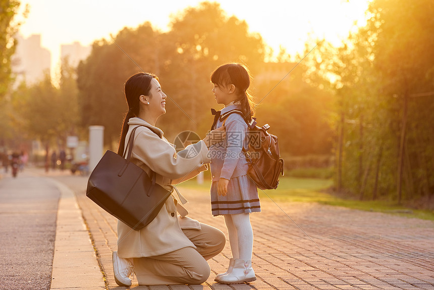 夕阳下妈妈为女儿整理衣服图片