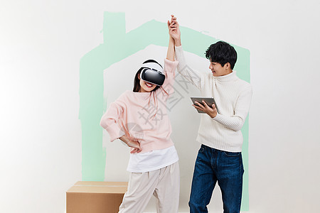 青年情侣在新家客厅使用VR设备图片