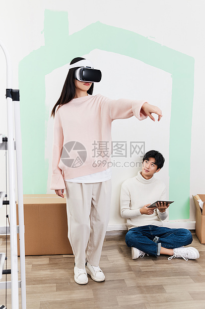 青年情侣在新家客厅使用VR设备图片