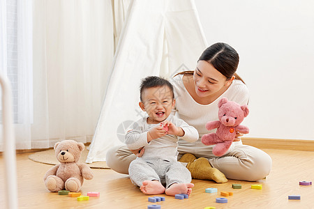 坐在地上的女人妈妈和孩子坐在地上一起玩耍背景