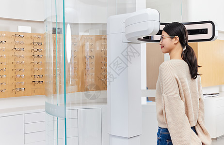 年轻女性站在验光机器前检查视力图片