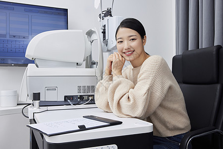 检查视力的女性坐在验光机器前面带微笑图片