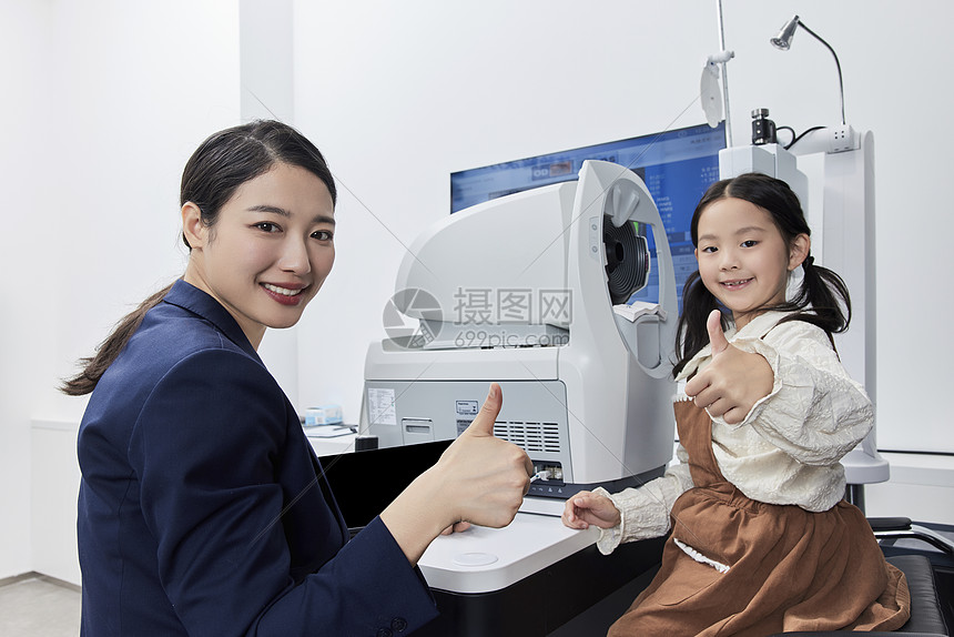 小女孩和验光师在验光机器前竖起大拇指图片