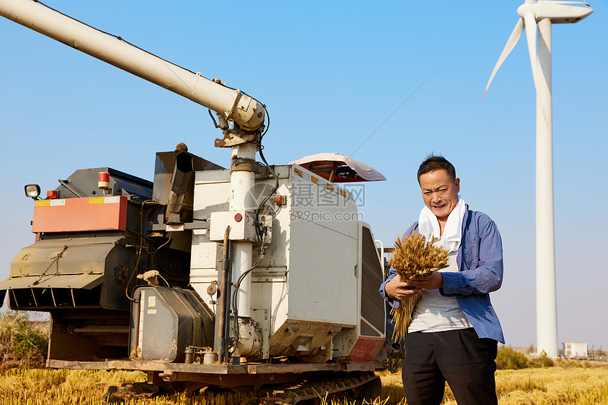 站在收割机前的农民形象图片