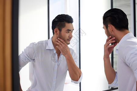 成熟男人站在镜子前整理胡子图片