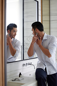 在卫生间对着镜子刮胡子的成熟男性图片