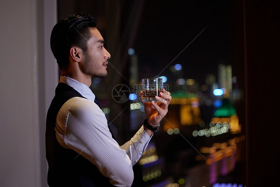 商务男士端着酒杯站在窗前图片