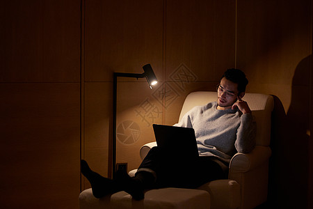 夜晚的室内夜晚躺在沙发上使用电脑的成熟男性背景