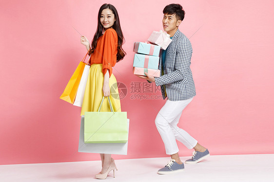 粉色背景购买时尚年轻情侣拿着购物袋图片