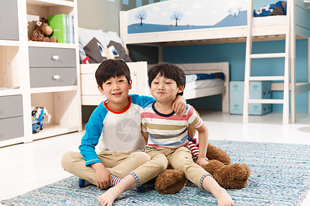 两个男孩坐在卧室的地毯上图片