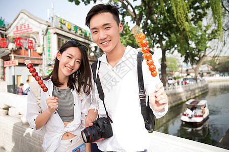 旅途青年情侣旅游拿着糖葫芦图片